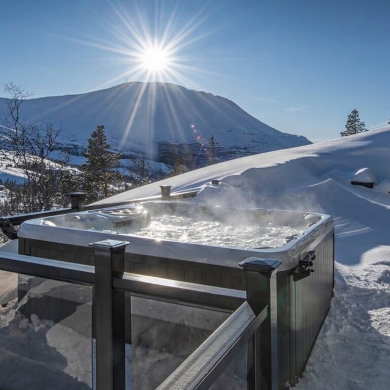 A hot tub steaming with snowy mountains in the background. Hot tub health benefits.